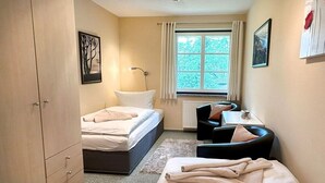 Ein Schlafzimmer mit einem Bett, einem Schreibtisch und einem Stuhl. Es gibt ein Fenster mit Vorhängen.