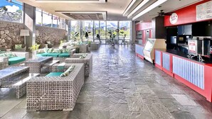 A spacious indoor area with wicker furniture, a stone wall, and a red counter with a menu. - 40F-High Floor-Stunning Ocean View-1 Bedroom Condo-Waikiki Beach (Honolulu)