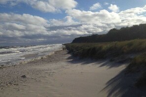 Ein Strand mit sandigem Ufer und einer grasbewachsenen Böschung.