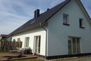 Een gelijkvloers huis met een schuin dak, grote ramen en een terras.