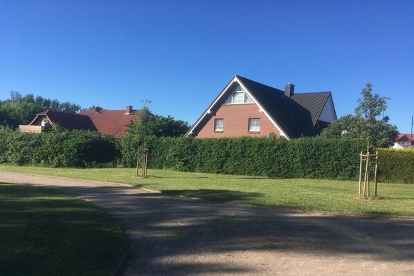 A residential house with a sloped roof, a brick facade, and a well-maintained lawn. - Holiday apartment MEERzeit (Rerik)