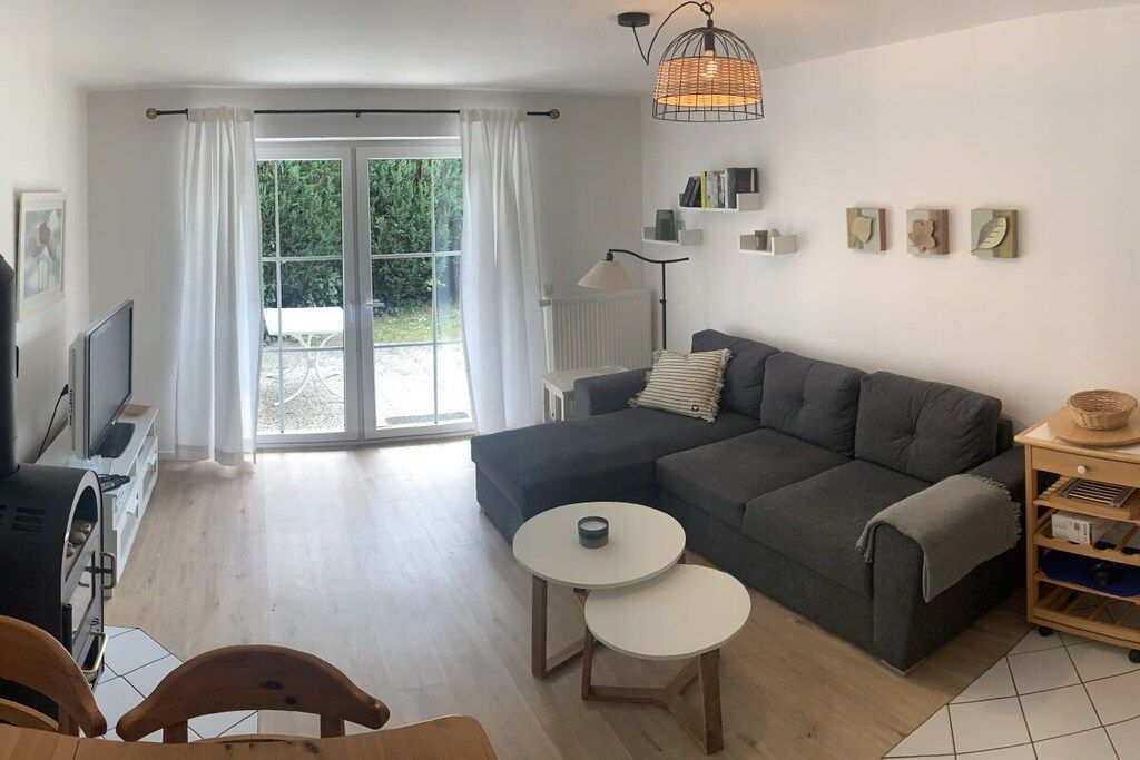 Ett modernt vardagsrum med en soffa, två små bord, en tv och en öppen spis.
