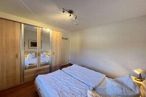 Ett sovrum med en säng, en garderob, en spegel och en sänglampa.