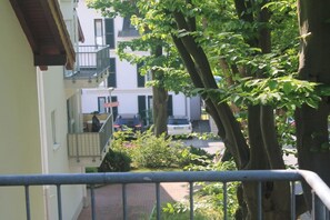 A residential area with a balcony, a white car parked on the street, and trees. - Holiday apartment with 1 bedroom (Sassnitz)