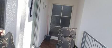 Uma varanda com mesa e cadeiras, uma janela e uma porta.