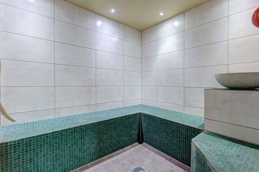 A corner of a room with tiled walls and a green-tiled bench.