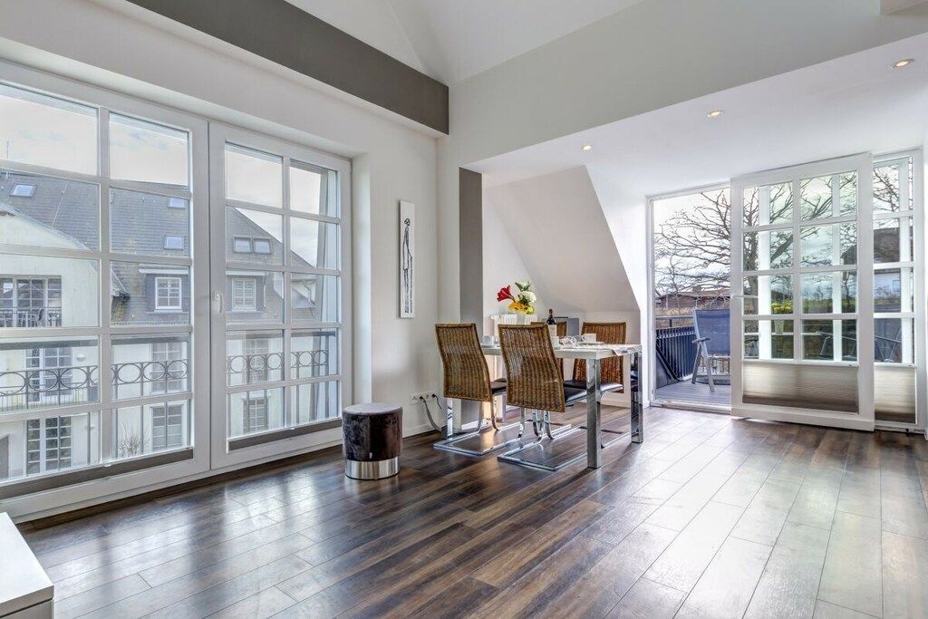 Una habitación amplia con ventanas grandes, una zona de comedor con sillas y vistas al exterior.