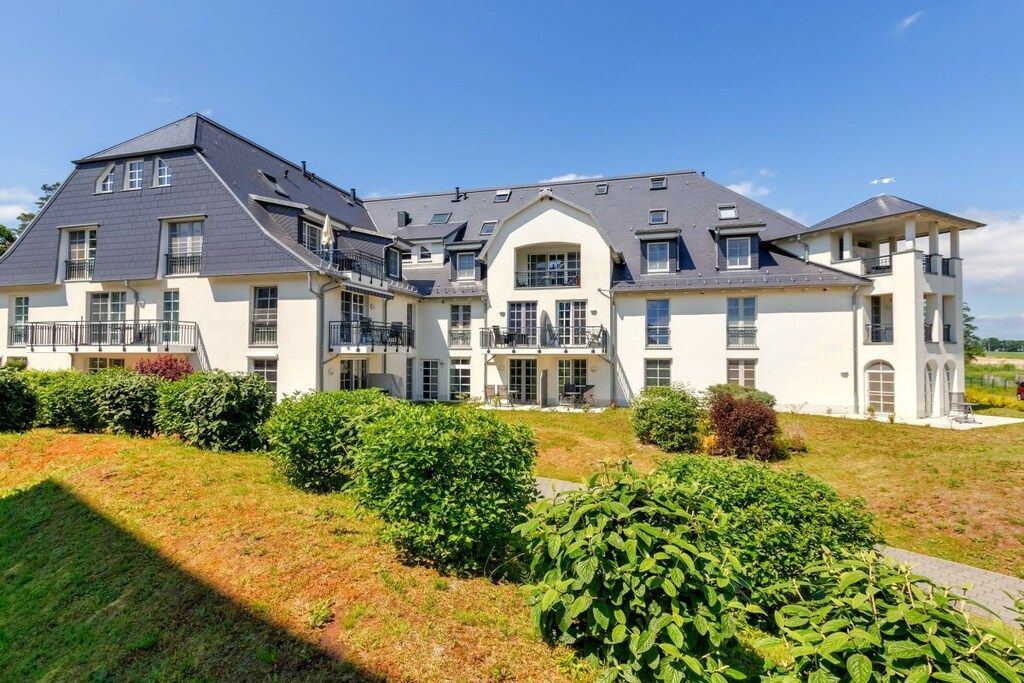 Uma casa grande, de vários andares, com fachada simétrica, várias varandas e um gramado bem cuidado.