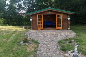 A wooden cabin with a stone-paved entrance, two chairs, and a table inside. - Holiday apartment with 2 bedrooms (Wiepkenhagen)