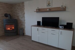 A living room with a fireplace, a television, and a cabinet. - Holiday apartment with 2 bedrooms (Wiepkenhagen)