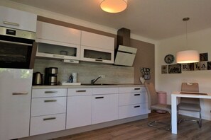 Eine moderne Küche mit weißen Schränken, einem Backofen und einer Kaffeemaschine.