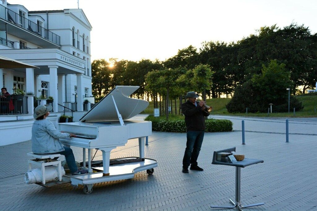 A portable piano set up in an outdoor area with a building in the background.