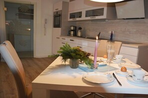 A dining area with a table set for a meal, a candle, and a potted plant. - Holiday apartment with 1 bedroom (Ostseeheilbad Zingst)