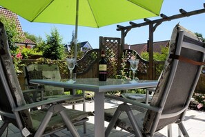 An outdoor patio with a table and chairs, a bottle of wine, and a green umbrella. - Holiday apartment with 1 bedroom (Ostseeheilbad Zingst)