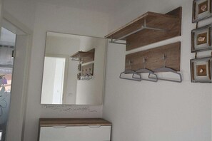 A bathroom with a large mirror, wooden shelves, and framed pictures on the wall. - Holiday apartment with 1 bedroom (Ostseeheilbad Zingst)
