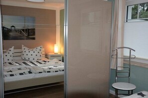 A bedroom with a bed, bedside table, lamp, and a chair. - Holiday apartment with 1 bedroom (Ostseeheilbad Zingst)