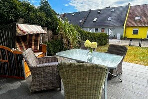 An outdoor patio with wicker furniture, a glass table, and a striped awning. - Holiday home in Pruchten with swimming pool (Pruchten)