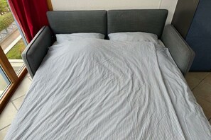 Een bed met grijze beklede hoofdeinden en een gestreept dekbed.
