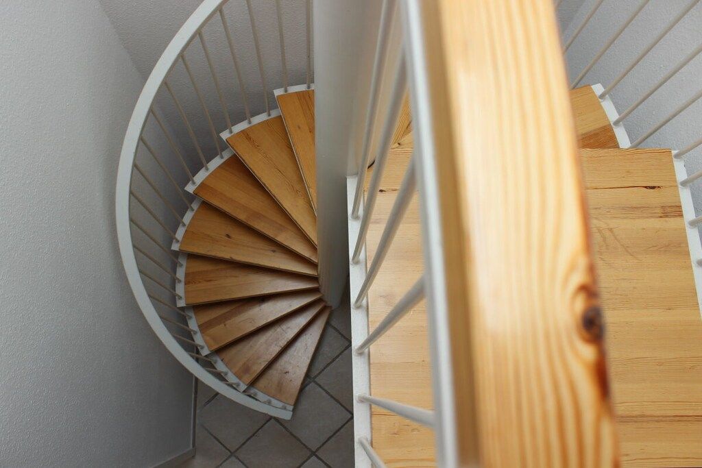 A spiral staircase with wooden steps and white railings.