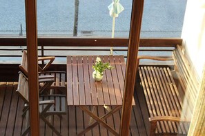 A wooden deck with a table and chairs, a potted plant, and a view of the water. - House Mecklenburg 21 (Kühlungsborn)