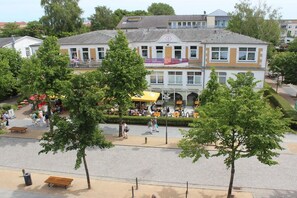A public square with a building featuring a central entrance and a café with outdoor seating. - House Mecklenburg 21 (Kühlungsborn)