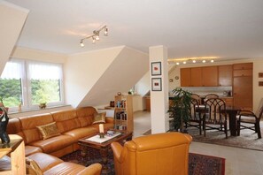 Ein Wohnzimmer mit einer Couch, einem Couchtisch und einem Essbereich mit Stühlen und einem Tisch.
