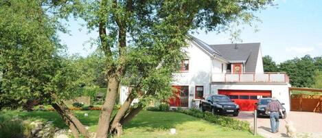 A two-story house with a garage, surrounded by a well-maintained lawn and trees.