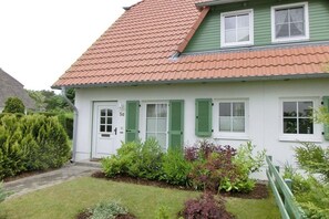 A white house with green shutters and a red-tiled roof. - Dune Resort Lindenweg (Karlshagen)