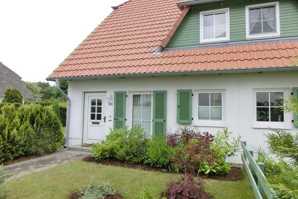 Et hvidt hus med grønne skodder og rødt tegltag.