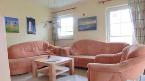 Uma sala de estar com dois sofás, uma mesa de centro de madeira e um abajur.