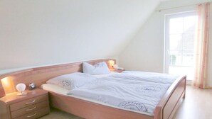 Quarto com uma cama de solteiro, mesas de cabeceira e janela com cortinas.