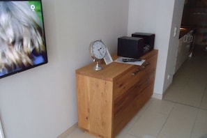 A wooden desk with a clock, a black box, and a remote control. - Miramare with sun terrace (Kühlungsborn)