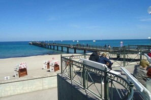 A pier extending into the sea with people walking and sitting on benches. - Miramare with sun terrace (Kühlungsborn)