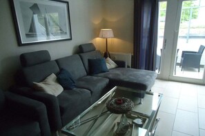 A modern living room with a sectional sofa, a glass coffee table, and a framed picture on the wall. - Miramare with sun terrace (Kühlungsborn)