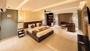 Een moderne hotelkamer met een groot bed, een zithoek, een televisie en een minibar.