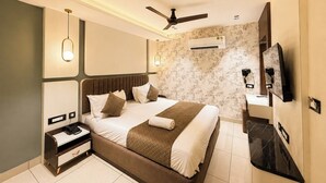Een moderne hotelkamer met een groot bed, nachtkastje en een flatscreen televisie aan de muur.