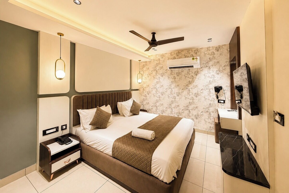 Ein modernes Hotelzimmer mit einem großen Bett, einem Nachttisch und einem flachbildfernseher an der Wand.