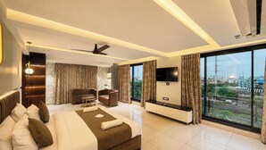 Een moderne hotelkamer met een groot bed, een zithoek, een flatscreen televisie en uitzicht op de stad.