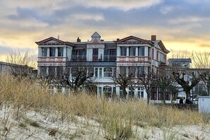 Un edificio grande de varios pisos con un estilo arquitectónico clásico, que destaca por su entrada principal y numerosos ventanales.