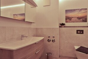 Une salle de bain moderne avec un grand miroir, un lavabo et des toilettes.