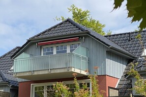 A residential building with a balcony, a pitched roof, and a visible window. - Holiday apartment with 3 bedrooms (Bansin)