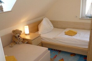Ein Kinderzimmer mit Bett, Nachttisch, Teddybär und Lampe.