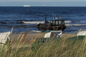 Ein Boot liegt vor der Küste mit Wellen im Hintergrund.