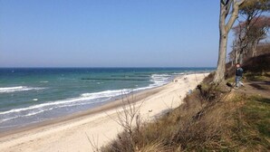 A beach with a sandy shore, a person walking along a path, and the ocean in the background. - Holiday apartment with 2 bedrooms (Börgerende)