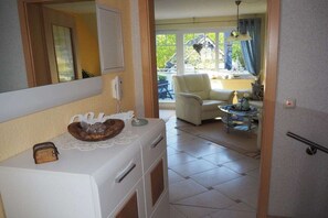 A compact living space with a kitchenette, a dining area, and a window with curtains. - Holiday apartment with 1 bedroom (Zingst)