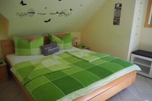 Een slaapkamer met een bed, kussens, een nachtkastje en een wand met decoratieve details.
