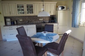 A kitchen with a round dining table, four chairs, a microwave, and cabinets. - Holiday apartment with 1 bedroom (Zingst)