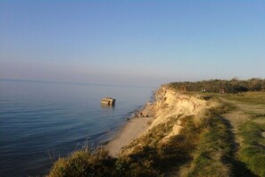 Eine Küstenlandschaft mit Sandstrand, einem Grasweg und blauem Himmel.