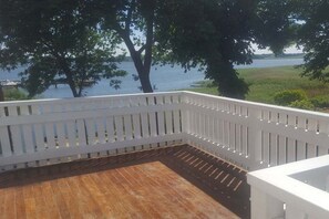 A wooden deck with a white railing overlooking a body of water and greenery. - Holiday apartment in Ziemitz with Wi-Fi (Ziemitz)