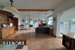 Ein geräumiges Wohnzimmer mit Kamin, Essbereich und einer Küche im Hintergrund.
